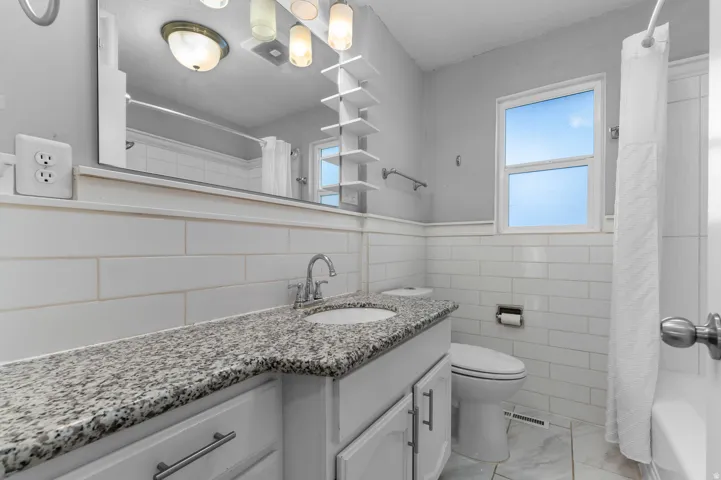 Vanity with granite countertop, undermount sink, and chrome faucet