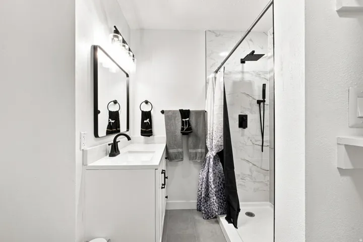 White vanity with a quartz countertop, rectangular undermount sink, and matte black faucet