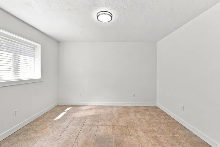Recessed lighting fixture, window with blinds, tile flooring, white walls, and white trim