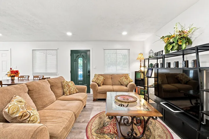 Open concept living area with wood-finish flooring, recessed lighting, and a decorative front entry door