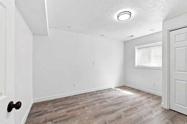 Wood-finish flooring with white walls, a single window, and a built-in closet