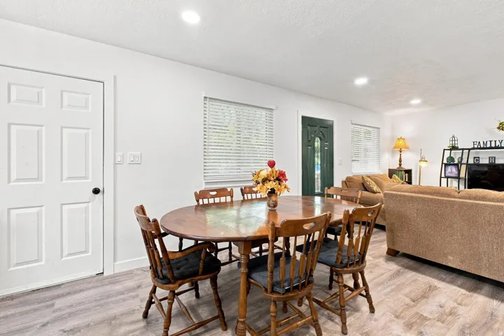 Recessed ceiling lighting, white interior walls, white paneled interior door, gray wood-finish flooring, and a dark green paneled exterior door