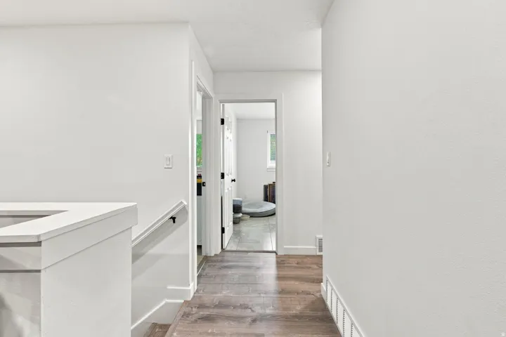 Hallway with wood-finish flooring, white walls, and white trim