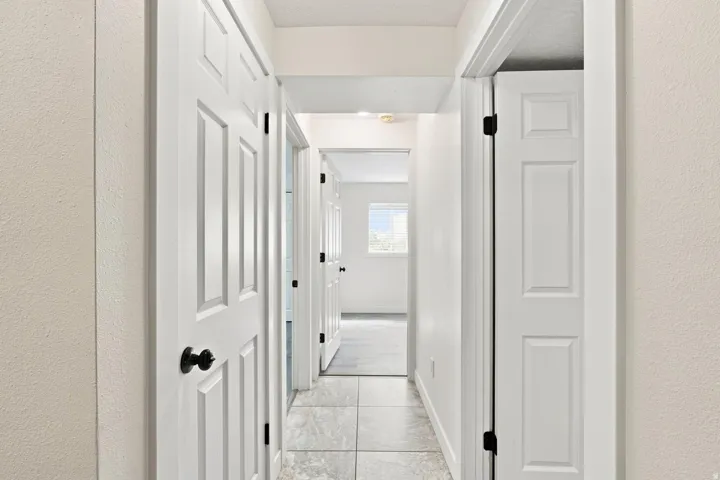 Hallway with white paneled doors, matte black hardware, and tiled flooring