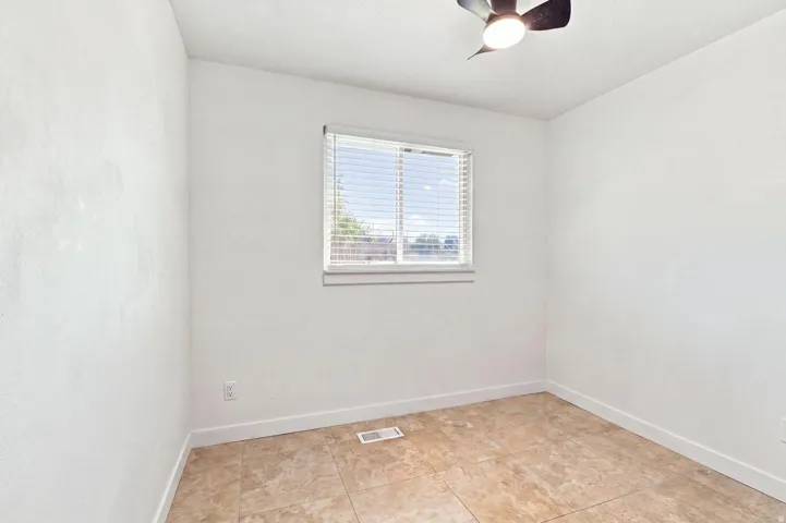 Tile flooring, window with blinds, ceiling fan with integrated lighting, and white walls