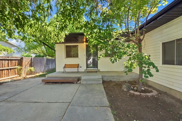 Concrete patio with a wood-finish platform, privacy fencing, and mature trees