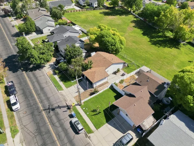 Asphalt shingle roofing, paved driveway, concrete sidewalks, and mature trees