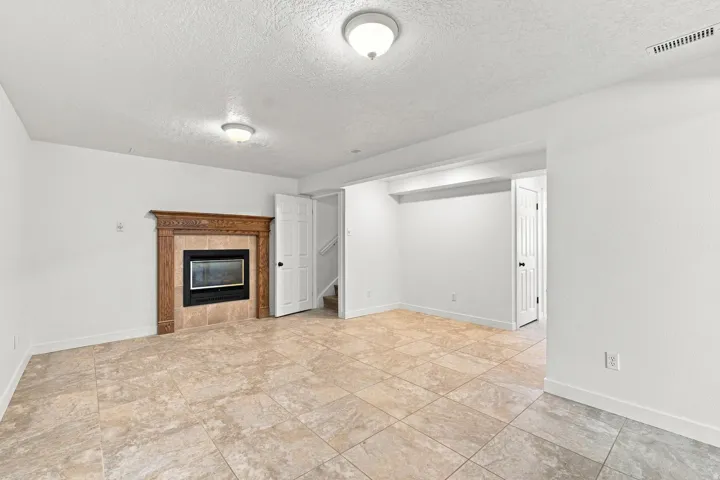 Recessed gas fireplace with decorative wood mantel, tiled surround, and hearth