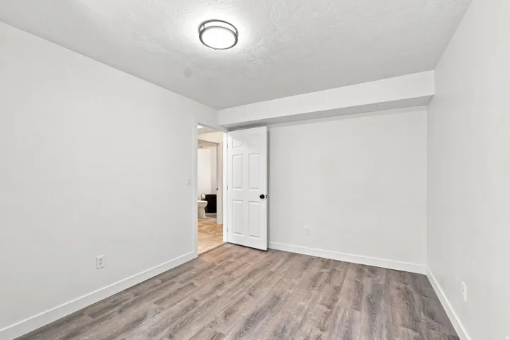 Wood-finish flooring with white walls and a ceiling-mounted light fixture