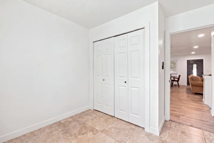 Tiled flooring, white bi-fold closet doors, and light wood-finish flooring