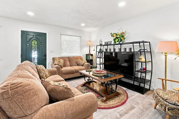 Recessed lighting, light wood-finish flooring, white walls, and a decorative front entry door