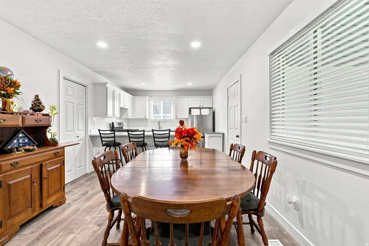 Recessed lighting, wood-finish flooring, white walls, white window blinds, and white kitchen cabinetry