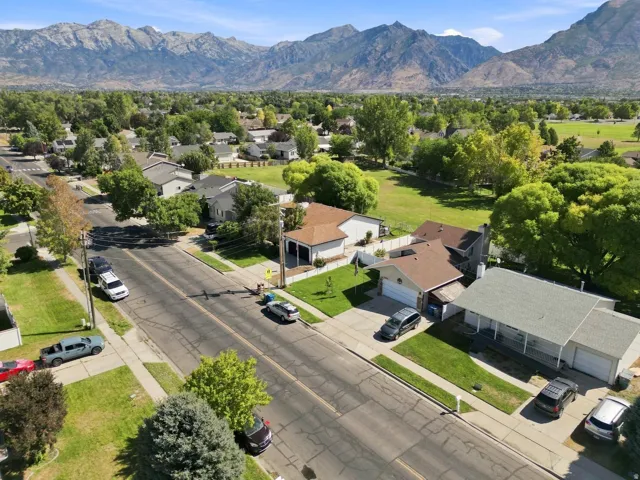 Residential property with attached garage, mature trees, and a mountain backdrop