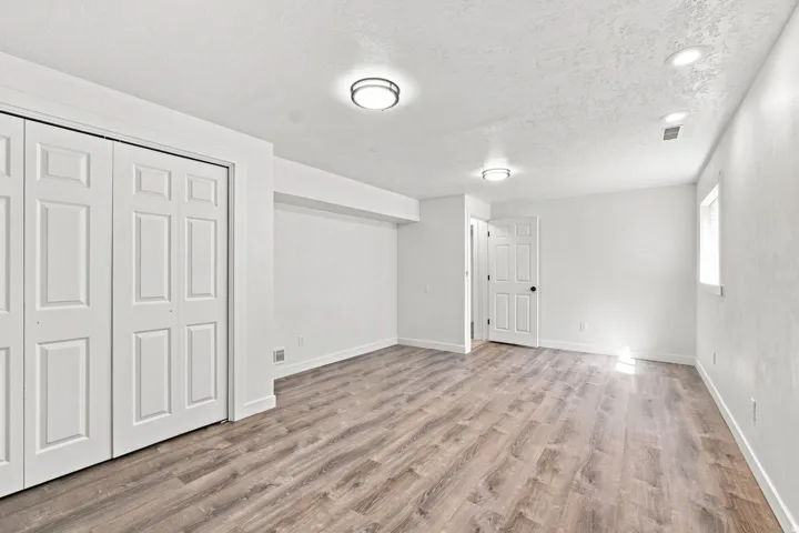Wood-finish flooring, white paneled doors, ceiling-mounted lighting, and recessed lighting