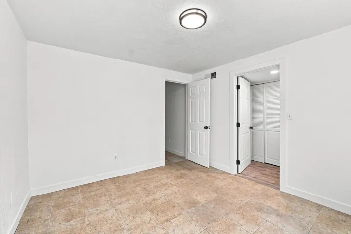 Neutral tone wall finishes, flush mount ceiling light fixture, white interior doors with black hardware, and tile flooring