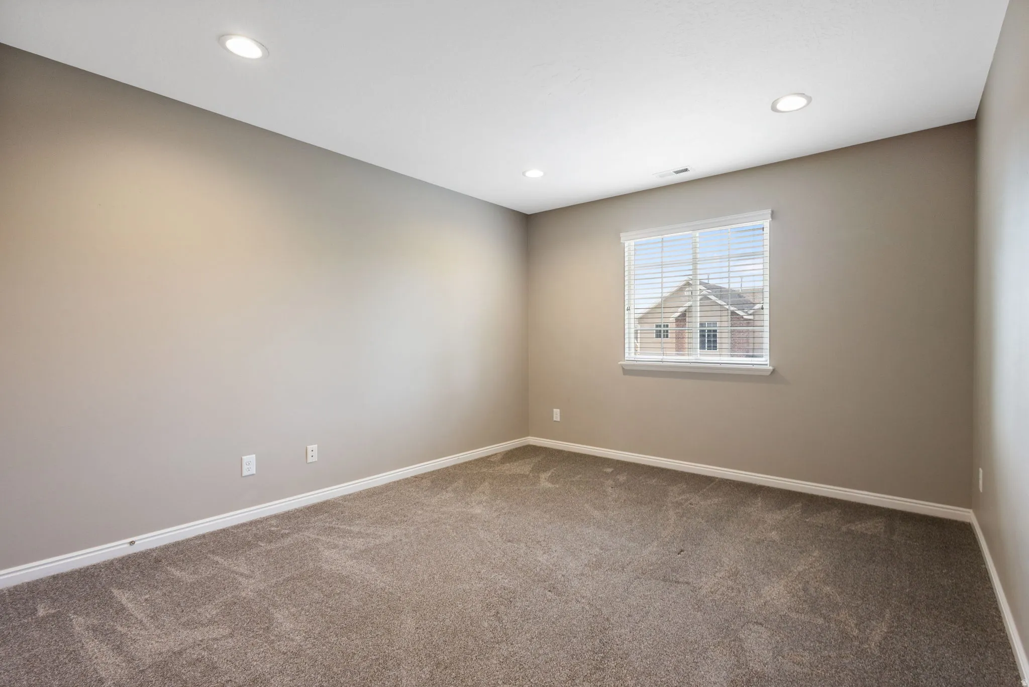 Recessed lighting illuminates neutral-toned walls and plush carpet flooring