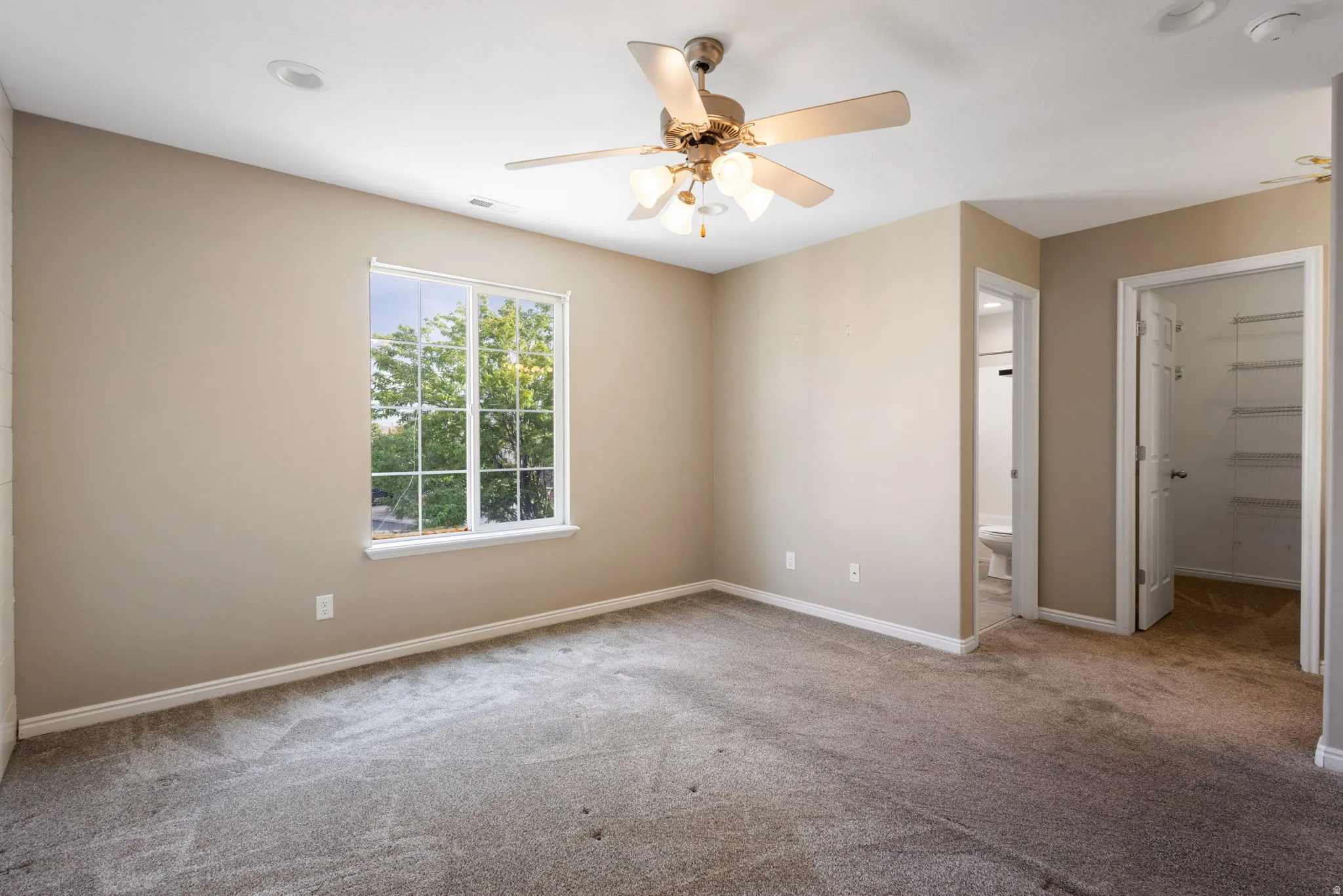 Carpeted room featuring a ceiling fan with integrated lighting, a window, and recessed lighting