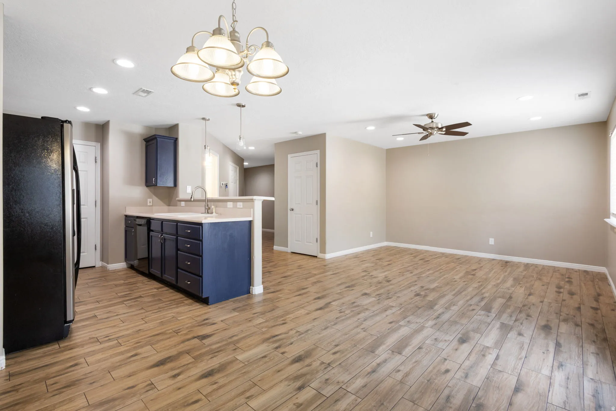 Open-concept living area with wood-finish flooring, recessed lighting, and a ceiling fan