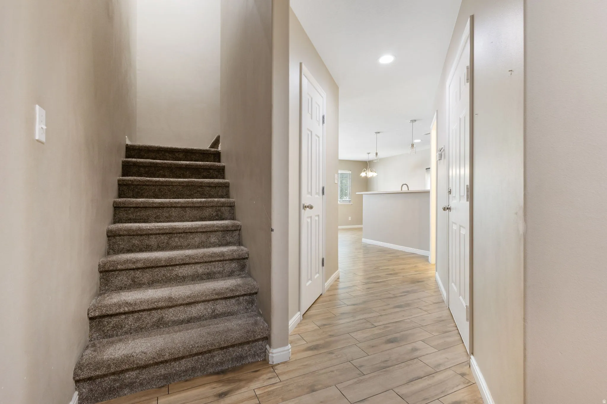 Carpeted staircase, wood-finish flooring, recessed lighting, and white panel doors