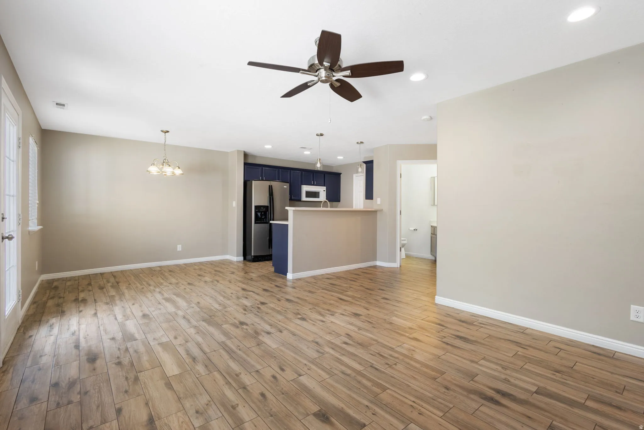 Open-concept living space with wood-finish flooring, a contemporary ceiling fan, and recessed lighting
