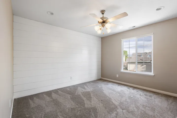 Accent wall with horizontal paneling, ceiling fan with light fixture, recessed ceiling lighting, and a large window