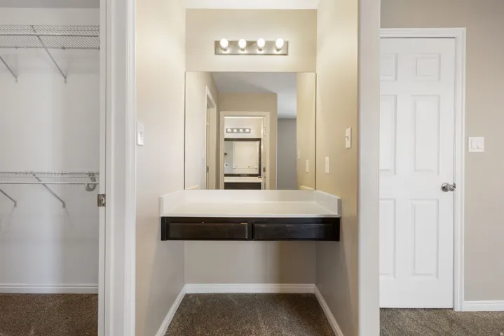 Built-in vanity with a countertop, integrated mirror, and overhead lighting