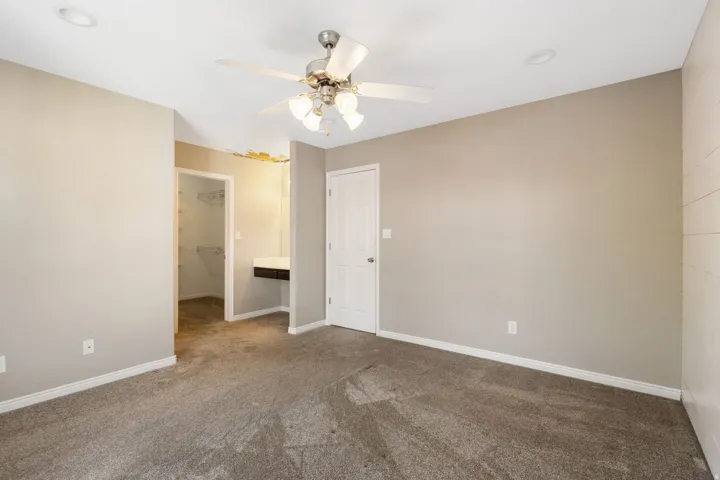 Recessed ceiling lighting, ceiling fan with integrated lighting, carpeted flooring, built-in vanity, and an integrated closet system