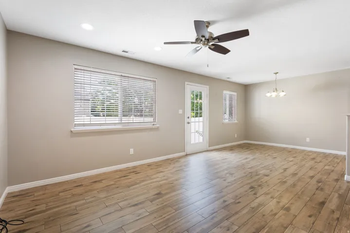 Spacious room featuring wood-finish flooring, a ceiling fan, and recessed lighting