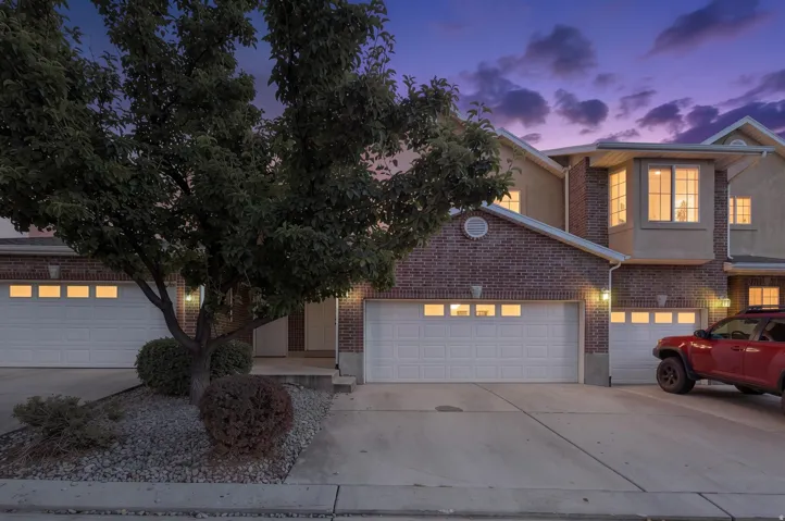 Brick and stucco facade with multiple garages, a bay window, and established landscaping