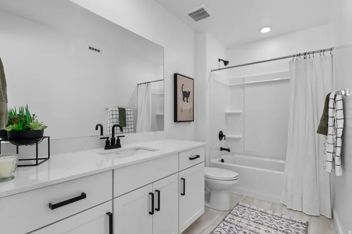 White vanity with a single basin, dark-finish faucet, and quartz countertop
