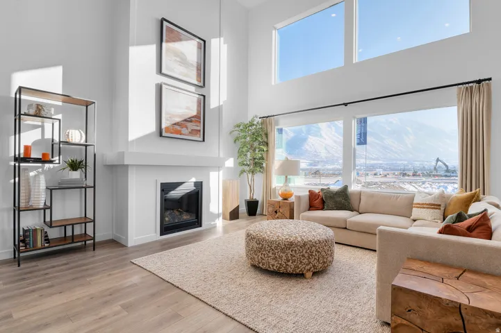 High ceilings and expansive windows illuminate the living area, featuring wood-finish flooring and a built-in fireplace