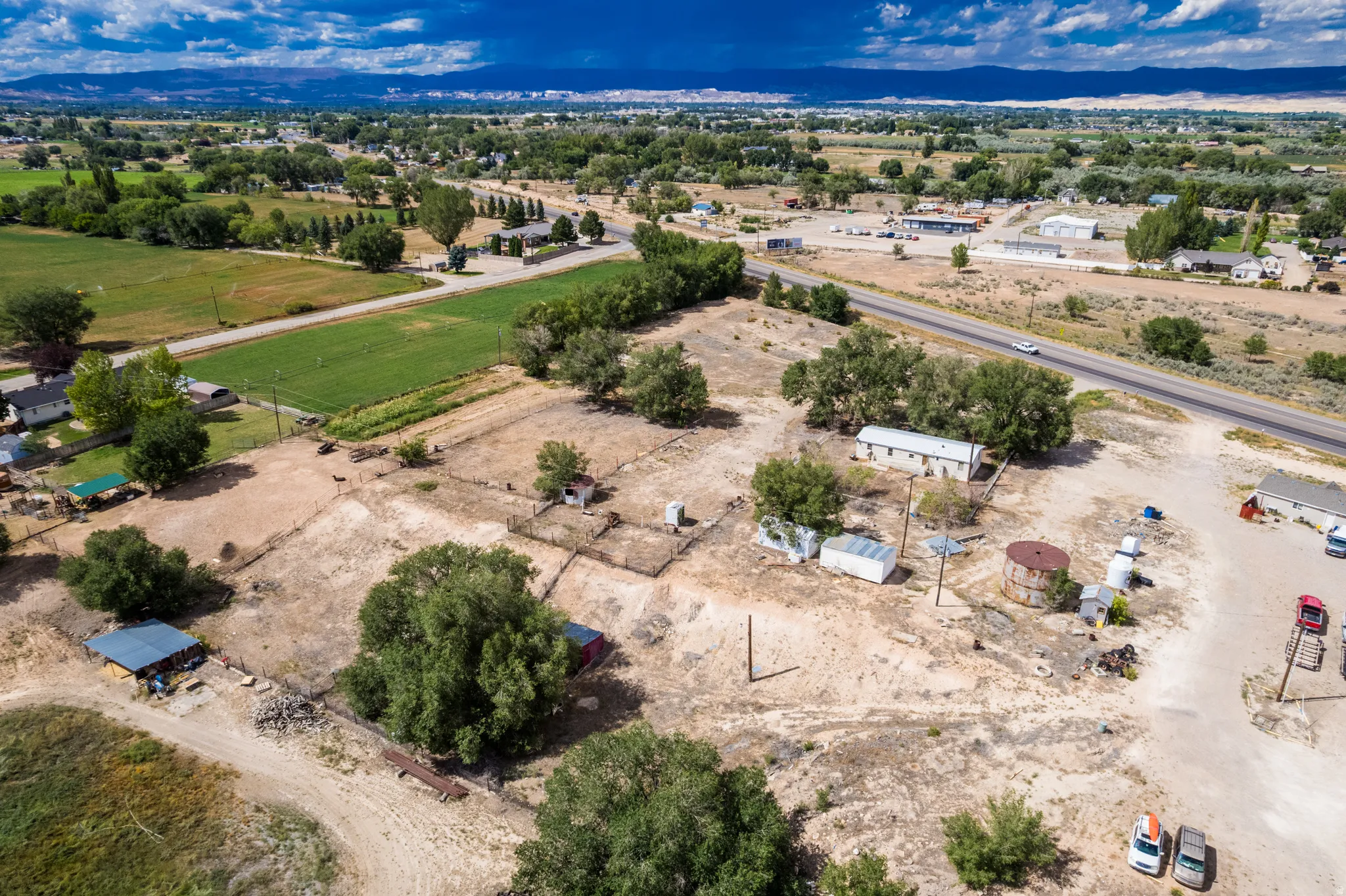 Expansive rural property featuring several structures, mature trees, and open land
