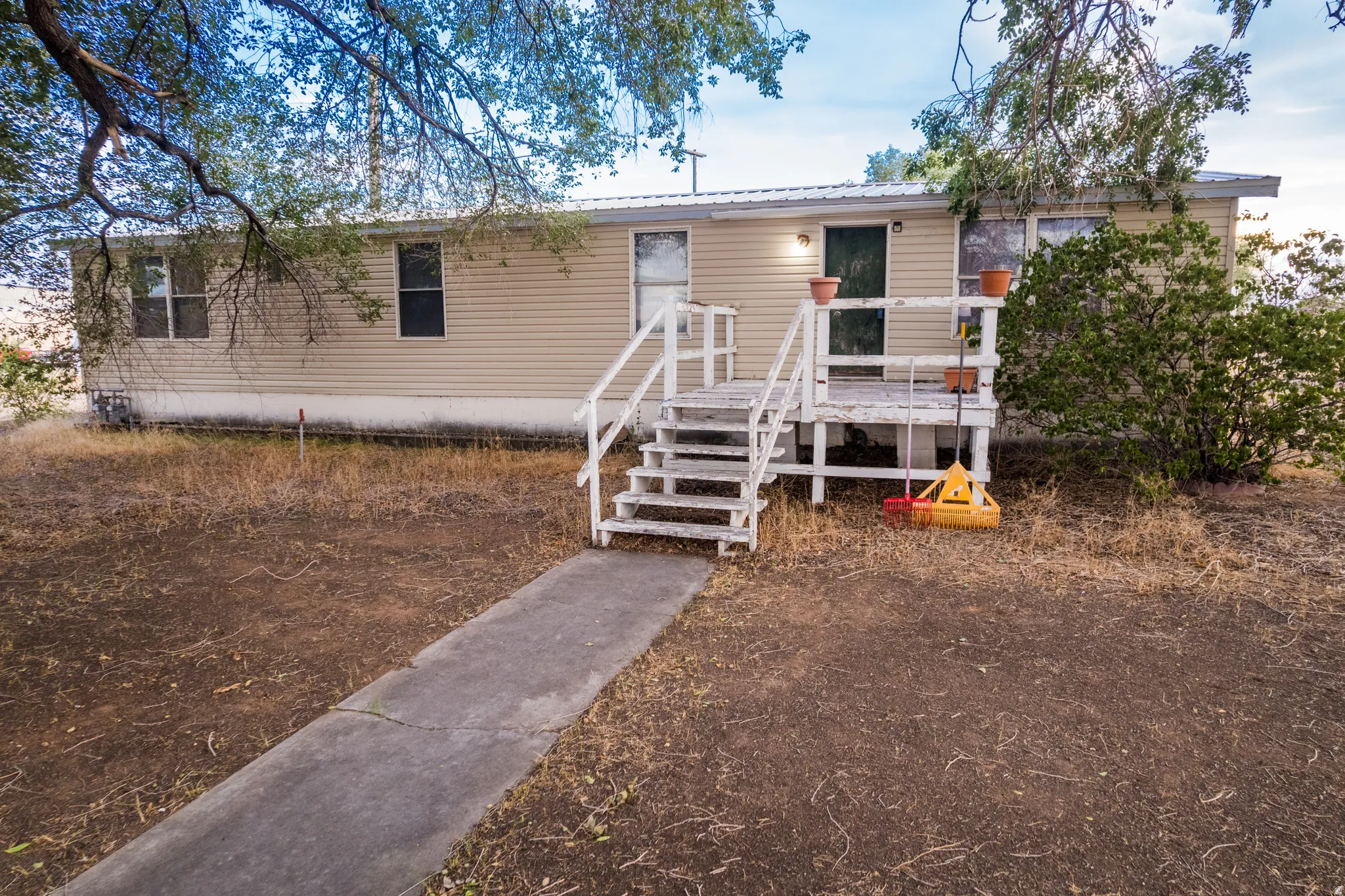 Front exterior featuring horizontal siding, a white wooden deck with railing, and a concrete walkway