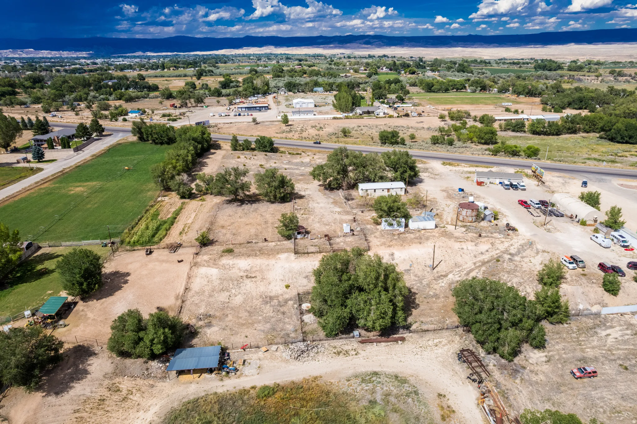 Expansive acreage featuring multiple outbuildings, mature trees, and direct road frontage