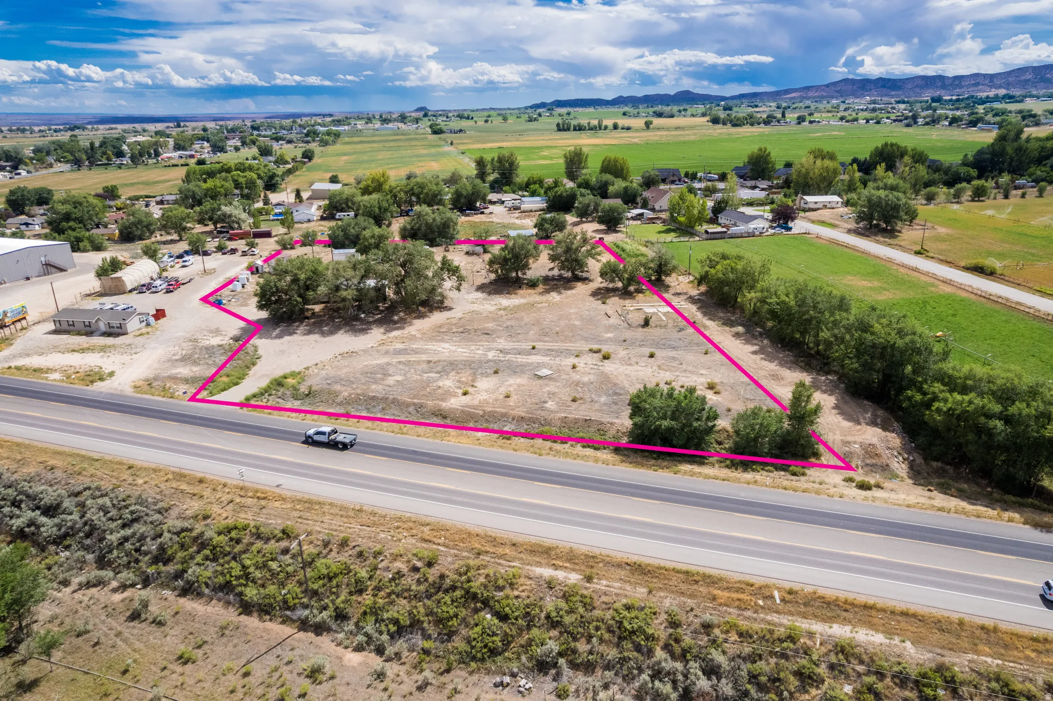Expansive undeveloped lot with direct road access, mature trees, and mountainous backdrop