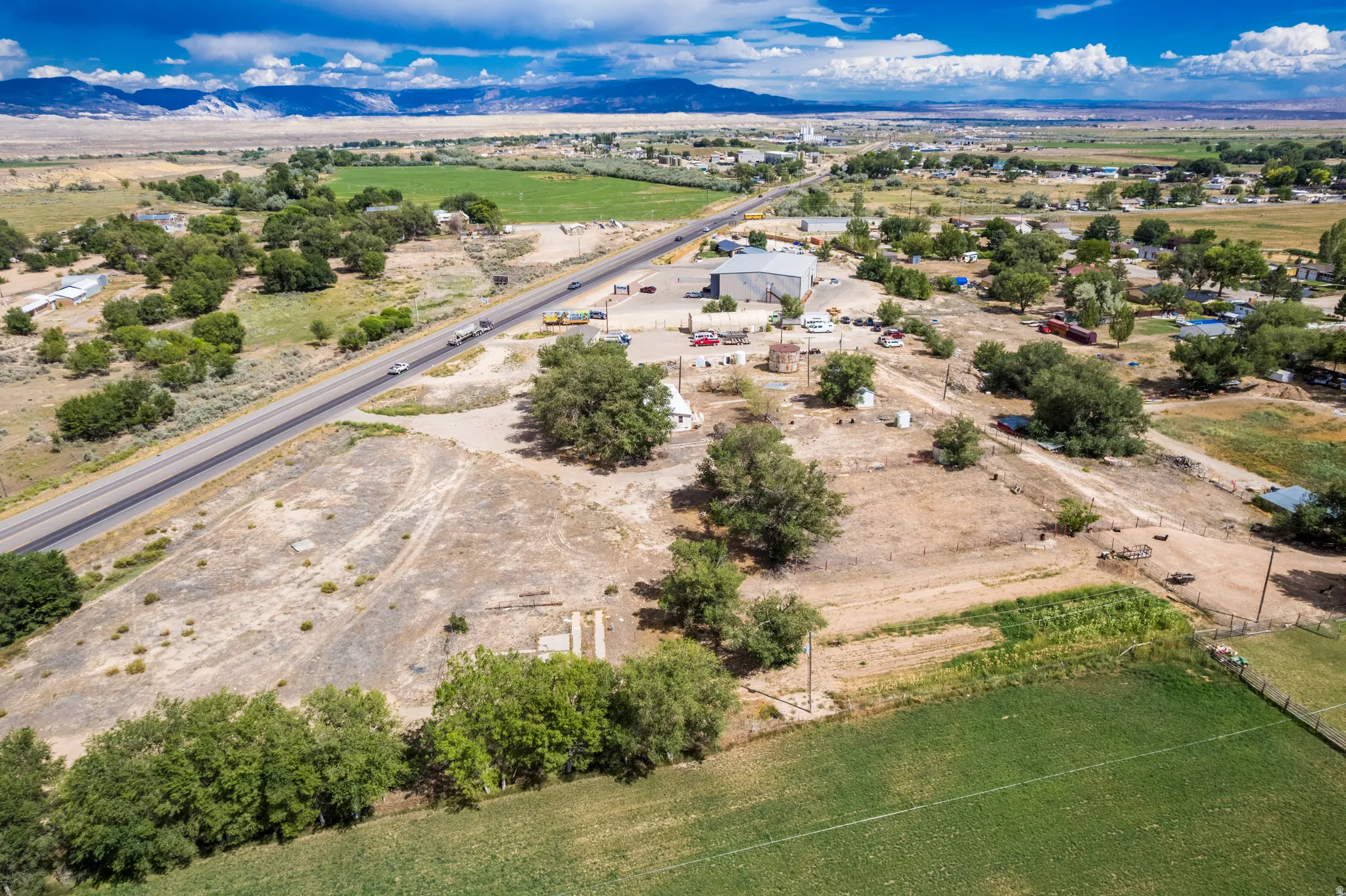 Expansive property featuring a paved roadway, mature trees, and agricultural fields