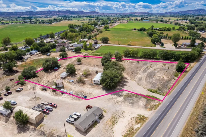 Expansive property featuring a defined lot boundary, adjacent roadway, and surrounding green fields