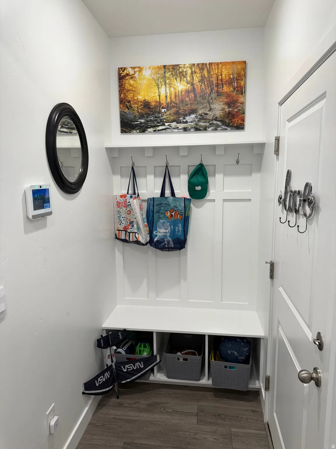 Entryway featuring a built-in bench with storage cubbies, wall-mounted coat hooks, and wood-finish flooring