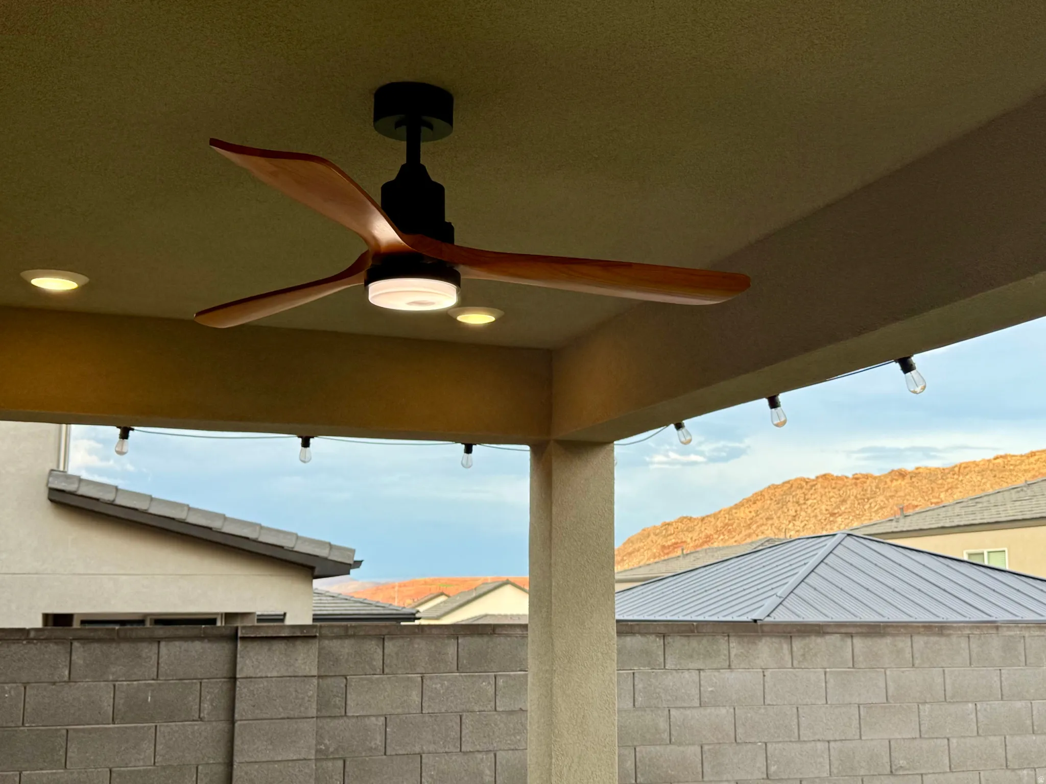 Covered patio featuring a wood-blade ceiling fan with integrated lighting, recessed ceiling lights, and string lighting