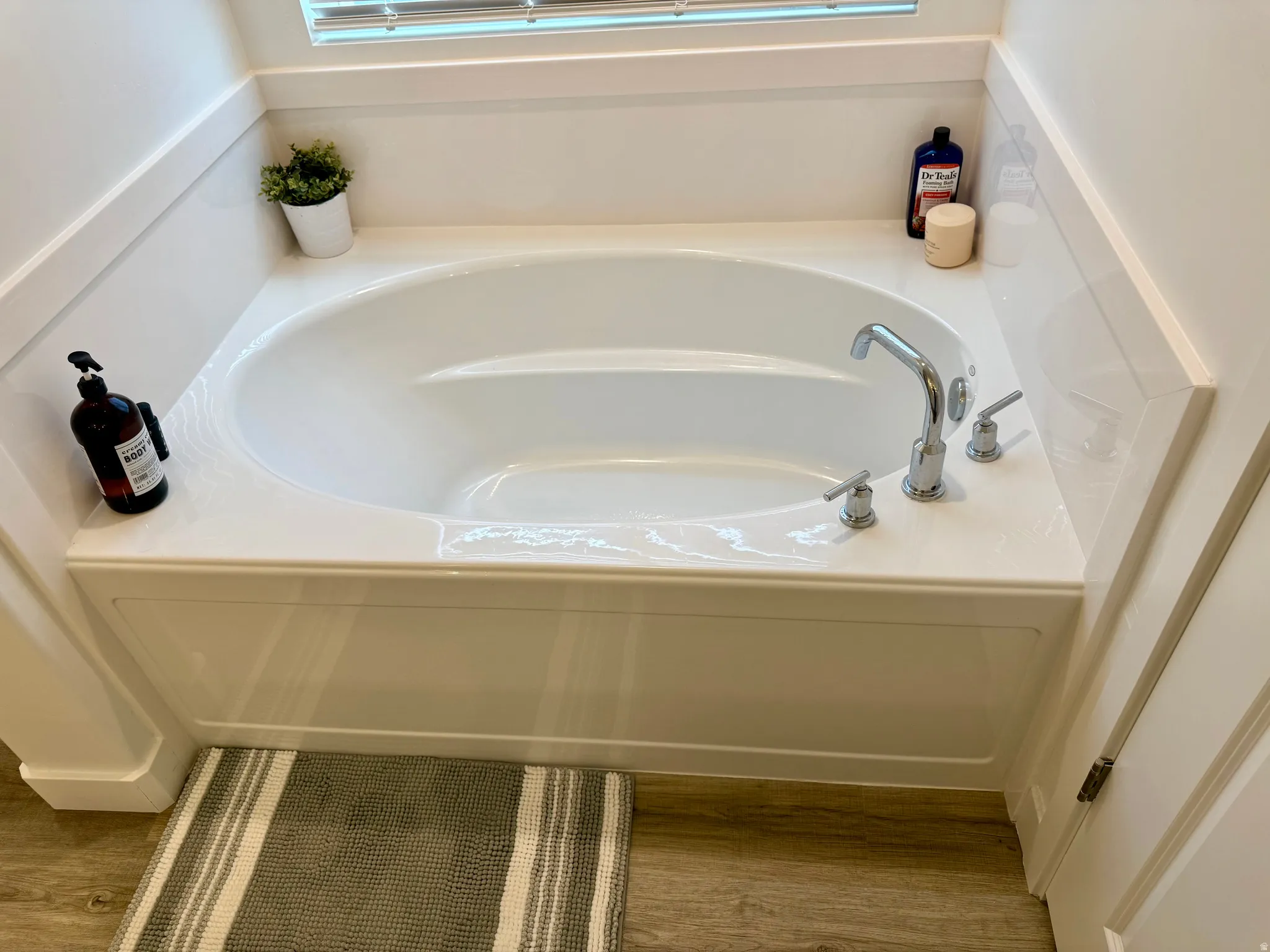 White drop-in bathtub with a polished chrome faucet and matching handles, set into a white paneled surround