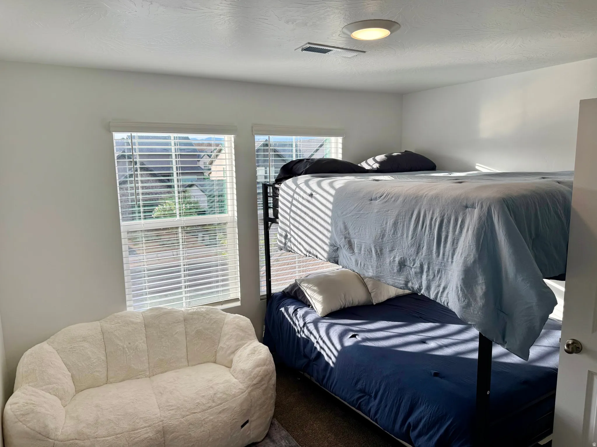 Bright interior space with dual windows, overhead flush-mount lighting, and white horizontal blinds