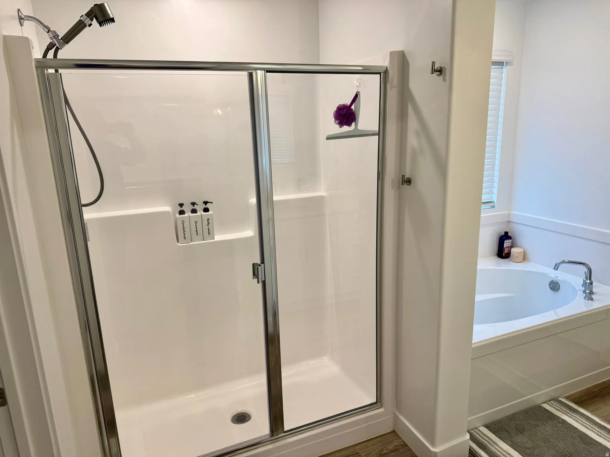 Enclosed shower with a sliding glass door and an adjacent built-in soaking tub featuring a chrome faucet