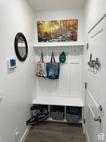 Entryway featuring a built-in bench with storage cubbies, wall-mounted coat hooks, and wood-finish flooring