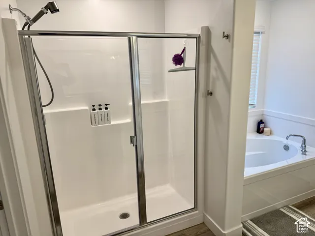 Enclosed shower with a sliding glass door and an adjacent built-in soaking tub featuring a chrome faucet