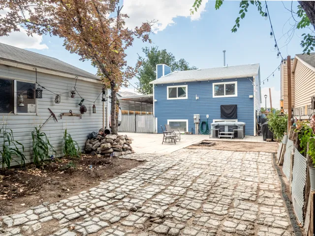 Expansive paver patio with an additional concrete pad, providing a built-in hot tub, and a detached structure with siding