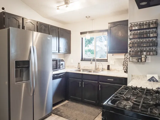 Kitchen featuring dark cabinetry, light countertops, stainless steel refrigerator, and a gas range