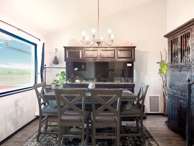 Vaulted ceiling with an elegant chandelier, large window, wood-finish flooring, and built-in cabinetry