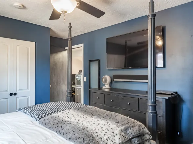 Blue-painted wall with a wall-mounted television and a ceiling fan with light fixture
