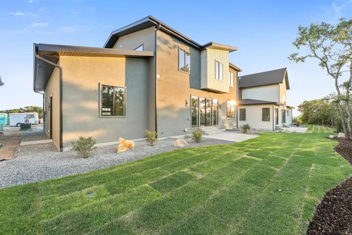 Modern exterior architecture with multiple window placements, a concrete patio, and a sloped lawn with mulched borders