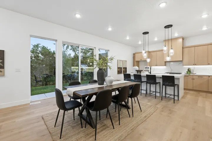Open-concept living space with wood-finish flooring, white walls, recessed lighting, and large sliding glass doors